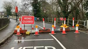 Roadworks and orange traffic cones on a UK high street, illustrating winter highway closures for town council event planning.